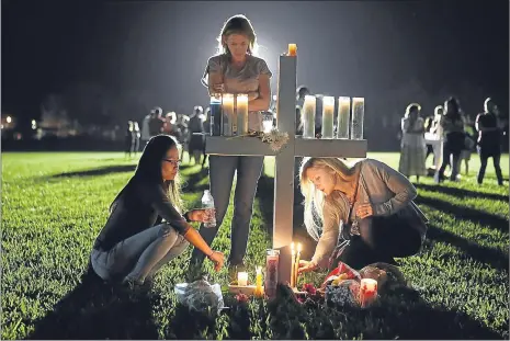  ??  ?? Students Maria Reyes, Stacy Buehler and Tiffany Goldberg light candles at a service for the victims of the shooting at Marjory Stoneman Douglas High School in Florida