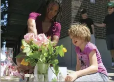  ??  ?? Angel Sauls (left), helps her stepdaught­er, Coco Douglas arrange a sign and some painted rocks she made for a memorial in Portland, Ore., on Saturday for two bystanders who were stabbed to death Friday while trying to stop a man who was yelling...