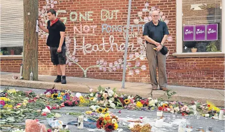  ?? Picture: AP. ?? Jason Charter, left, of Washington, stands by a memorial to Heather Heyer at the spot where she was killed. Charter was at the scene when a car rammed into anti-fascist demonstrat­ors.
