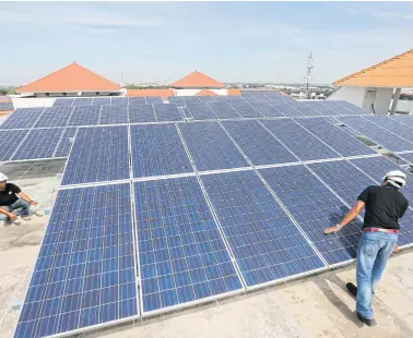  ?? PATTANAPON­G HIRUNARD ?? Workers install solar panels on the roof of Thammasat University Hospital.