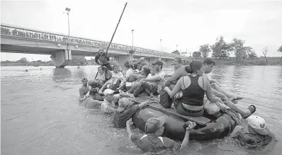  ?? AP Photo/Moises Castillo ?? ■ A group of Central American migrants crosses the Suchiate River aboard a raft made out of tractor inner tubes and wooden planks Saturday on the the border between Guatemala and Mexico in Ciudad Hidalgo, Mexico.