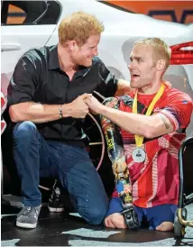  ??  ?? Embrace: Harry awards a silver medal to Mark Ormrod at the Invictus Games. The ex Marine, below, lost both legs and an arm in Afghanista­n