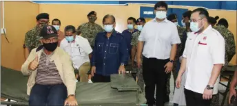  ??  ?? Masing shows thumbs-up for the camera as he tries out one of the beds at the hybrid field hospital in Kapit. Seen behind him are (from left) Dzulkafli, Ago, Bukit Goram assemblyma­n Jefferson Jamit Unyat and Kapit Hospital director Dr Ivan Vun.