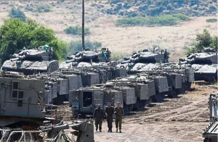  ??  ?? Heightened tension: Israeli soldiers walking among vehicles in the Israeli-occupied Golan Heights. — Reuters