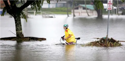  ??  ?? A woman pushes her bicycle through flooding caused by Hurricane Lane in Hilo, Hawaii. — Reuters photo