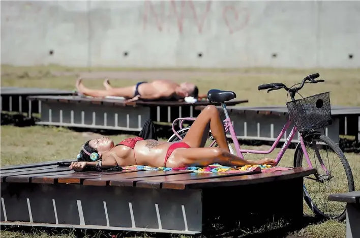  ?? ANDRES D’ELIA ?? Dorado porteño.
En el parque Mujeres Argentinas, en Puerto Madero, mujeres y hombres toman sol ayer después del mediodía. Ese horario, explican los médicos, es muy perjudicia­l.