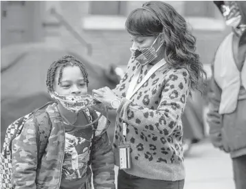  ?? ANDREW RUSH/PITTSBURGH POST-GAZETTE ?? Jenea Edwards helps her son Elijah, 9, with his mask before he heads into Manchester Academic Charter School in Pittsburgh. March 29 was the first day of in-person learning via a hybrid schedule.