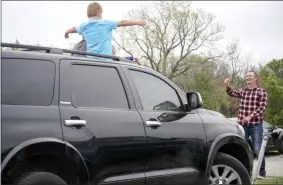  ?? IAN MAULE ?? In this Sunday, April 5, 2020 photo, Commongrou­nd Pastor Tom Dillingham gives a thumbs up to a car while a church goer gives a social distance appropriat­e hug during a drive-in church service at Admiral Twin Drive-in in Tulsa, Okla.