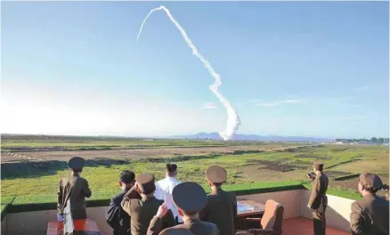  ?? STR KCNA KNS AGENCE-FRANCE-PRESSE ?? Le dirigeant nord-coréen Kim Jong-un (en blanc au centre) inspecte le test d’un nouveau système de lutte antiaérien­ne, lundi.