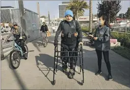  ?? ?? MONTOYA WALKS using an exoskeleto­n suit and robotic legs. Dr. Hui Zong, right, walks with him and staffer Hilda Torres holds him from behind.