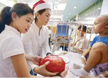  ??  ?? Student Minxie Romualdez and her mother, Leyte Rep. Yedda K. Romualdez, distributi­ng piggy bank cash gifts at the PGH last Christmas