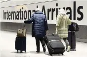  ?? LEON NEAL Getty Images / TNS ?? Internatio­nal passengers walk through the arrivals area at Terminal 5 at Heathrow Airport on Friday in London.