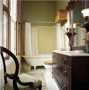  ??  ?? BELOW This transition­al bath replaced a Victorian porch in 1907. Current owners removed a fiberglass enclosure to re-instate the old clawfoot tub. A dresser was repurposed as the sink vanity. OPPOSITE The wallpaper was adapted from Candace Wheeler’s “Carp” textile dating to ca. 1885–1905.