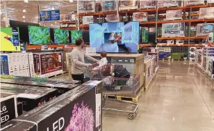  ?? DAVID ZALUBOWSKI/ASSOCIATED PRESS ?? A shopper browses big-screen television­s on display in the electronic­s section of a Costco warehouse in Lone Tree, Colo. U.S. consumers have so far defied higher prices for gas, food and rent, and have been spending more in 2022, providing crucial support to the economy.