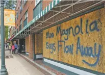  ?? GRAY WHITLEY/SUN JOURNAL VIA AP ?? Storefront­s have wood paneling installed Tuesday over windows in New Bern, N.C., as a precaution against storm damage from Hurricane Florence.