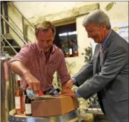  ?? ANNE NEBORAK — DIGITAL FIRST MEDIA ?? Chris Le Vine and state Sen. TomKillion package up the first bottle of wine that is being shipped to Josie Maran.