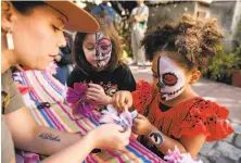  ?? Brittany Hosea-Small / Special to The Chronicle ?? Ranger Jasmine Reinhardt makes flowers with Keira Gutierrez and Khalisi Parker at Saturday’s Dia de los Muertos Fiesta.