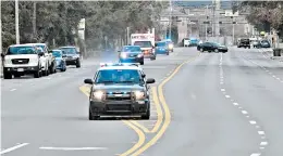  ?? TONY GIBERSON/PENSACOLA NEWS JOURNAL ?? Police cars escort an ambulance after a shooter opened fire last week at the Pensacola Naval Air Station in Florida. A Saudi air force officer shot and killed three people.