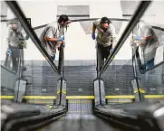  ?? Jon Shapley / Staff photograph­er ?? Zachary Pierson, left, and Ezequiel Erazo clean an escalator Friday at PlazAmeric­as mall in Houston.