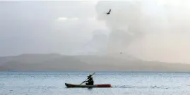  ?? REUTERS/ELOISA LOPEZ ?? A FISHERMAN paddles as the Taal Volcano continues to erupt in Talisay, Batangas, Jan. 14. The Agricultur­e department said around 6,000 fish cages in the lake are at risk.