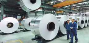  ?? WAN SHANCHAO / FOR CHINA DAILY ?? Two workers walk past a production line of an aluminum plant in Suixi county, Anhui province.