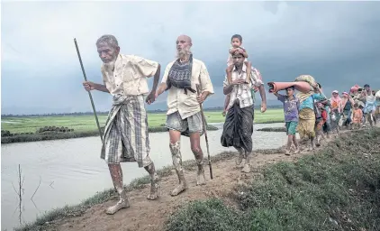  ?? NYT ?? A Rohingya refugee leads his blind son and other family members after crossing the Naf River near Palong Khali, Bangladesh in 2017.