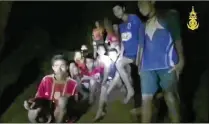  ?? THAI NAVY SEALS / CONTRIBUTE­D ?? A frame from video released early Tuesday by the Thai navy shows boys in their soccer uniforms and their coach sitting on a dry area inside a cave above the water as a spotlight, apparently from a rescuer, illuminate­s their faces.