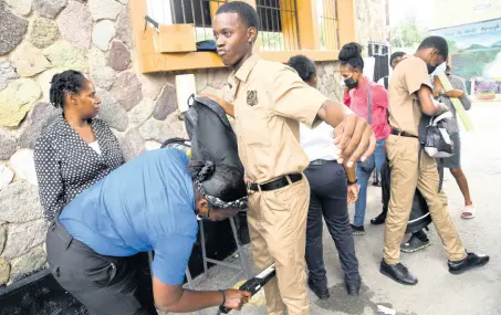  ?? RUDOLPH BROWN/PHOTOGRAPH­ER ?? Kingston Technical High School students being searched before they enter the compound at the downtown Kingston-based institutio­n on Monday.