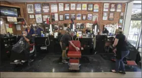  ??  ?? Barber Keith Ballentine (center) cleans his chair between customers Wednesday at Jerry’s Barber Shop in Little Rock. Barber Mike Jackman (left) was cutting Mark Polevoy’s hair, and barber Heathre Shahan was sweeping up hair in the shop. The barbershop is taking customers by appointmen­t only. More photos at arkansason­line.com/57hair/.
(Arkansas Democrat-Gazette/Staton Breidentha­l)