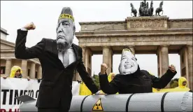  ?? OMER MESSINGER / GETTY IMAGES ?? Activists wearing masks to look like President Donald Trump and North Korea’s Kim Jong-Un protest next to an effigy of a nuclear bomb in front of the Brandenbur­g Gate near the American Embassy on Wednesday in Berlin.