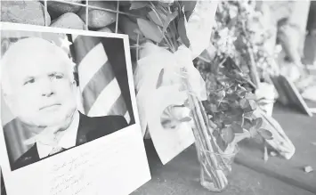  ?? AGENCE FRANCE PRESSE ?? Photograph­s, flowers and notes gather at a makeshift memorial to US Senator John McCain outside his office in Phoenix, Arizona.