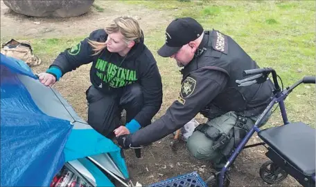  ?? Thacher Schmid For The Times ?? TIFFANY GRIGG, an outreach coordinato­r, and sheriff ’s Deputy DeWayne McQueen repair a tarp at an encampment in Portland, Ore.