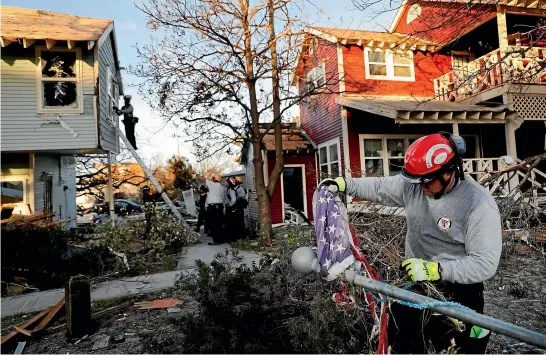  ?? AP ?? South Florida urban search and rescue specialist Chris Boyer removes a damaged American flag from a downed pole while checking for for survivors of Hurricane Michael in Mexico Beach, Florida.