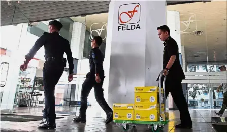  ??  ?? Investigat­ion haul: MACC officers taking away the three boxes of documents after almost eight hours of operation at the FIC office in Balai Felda, Kuala Lumpur.
