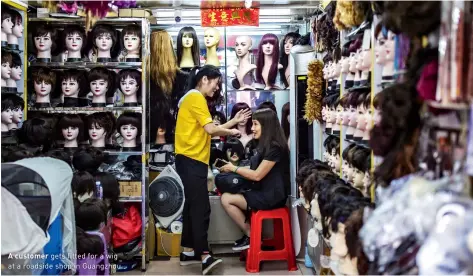  ??  ?? A roaster tosses the day’s pick to assist with oxidation
A customer gets fitted for a wig at a roadside shop in Guangzhou