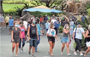  ?? JOHN RAOUX/AP ?? Guests wearing masks stroll through SeaWorld as it reopened with new safety measures in place Thursday in Orlando, Fla.