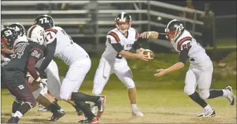  ??  ?? Brent Ferguson helps to hold off the Huntsville defense as Seth Brumley, No. 8, hands the ball off the Britton Caudill, No. 22.