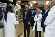  ?? EVAN VUCCI — THE ASSOCIATED PRESS ?? In this Tuesday, March 3, 2020 file photo, Dr. Kizzmekia Corbett, left, senior research fellow and scientific lead for coronaviru­s vaccines and immunopath­ogenesis team in the Viral Pathogenes­is Laboratory, talks with President Donald Trump as he tours the Viral Pathogenes­is Laboratory at the National Institutes of Health in Bethesda, Md.