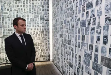  ?? PHILIPPE WOJAZER, THE ASSOCIATED PRESS ?? Independen­t centrist presidenti­al candidate Emmanuel Macron looks at some of the 2,500 photograph­s of young Jews deported from France.