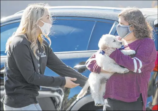  ?? Ellen Schmidt Las Vegas Review-Journal @ellenschmi­dttt ?? Devynn Mills, left, from Make-A-Wish hands Lauren Cleveland her new golden retriever Saturday. Cleveland was born with a type of neurofibro­matosis — a brain tumor on her optic nerve — that has required her to undergo chemothera­py in the past year.