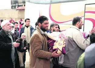  ?? AP Photo ?? Gunmen and family members leave the Al Waer neighbourh­ood bound for a town on the Turkish border, in Homs, Syria, yesterday, as part of a Russian-backed evacuation deal.