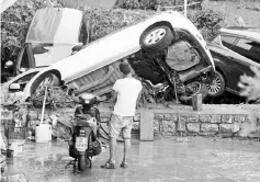  ??  ?? A man looks at damaged cars following floods in Livorno. — Reuters photo