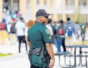  ?? RICARDO RAMIREZ BUXEDA/STAFF PHOTOGRAPH­ER ?? An Orange sheriff’s deputy watches students returning to class at Evans High School. Orange has approved Sheriff Jerry Demings’ request to hire 75 new deputies to serve as school resource officers.