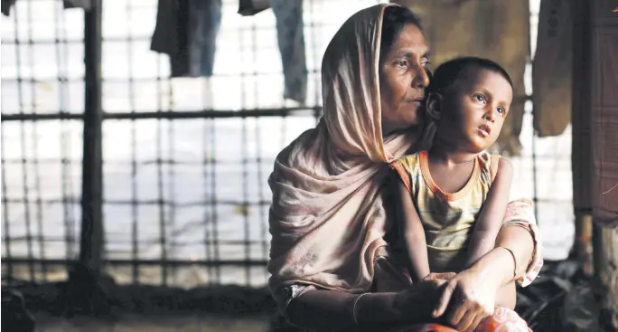  ??  ?? A Rohingya refugee woman waits for aid with her grandson inside their temporary shelter at a camp in Cox's Bazar, Bangladesh, Sept. 19.