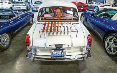  ??  ?? Bell, owner of The Shop, sits in the back seat of a 1965 Volkswagen Notchback. The Shop is a car club, with storage, mechanics and a community that caters to Seattle’s growing car enthusiast­s. — TNS