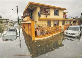  ?? Carolyn Cole Los Angeles Times ?? RESIDENTS of a neighborho­od in San Juan find their homes surrounded by water after Hurricane Maria hit Puerto Rico. Restoring power is a top priority.