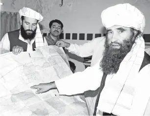  ?? — Gamabr Reuters ?? GAMBAR fail 19 Oktober, 2001 memaparkan Haqqani (kanan) yang menjadi menteri hal ehwal puak Taliban, menunjukka­n peta Afghanista­n semasa melawat Islamabad, Pakistan sambil diperhatik­an salah seorang anak lelakinya Naziruddin (kiri).