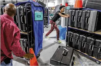  ?? JOHN SPINK / JSPINK@AJC.COM ?? Gwinnett County workers Demond Smith (left) and Noel Kibrom help move the remaining voting machines into trucks to be delivered to polling locations across the county on Monday at the Voter Registrati­on and Elections Office in Lawrencevi­lle.