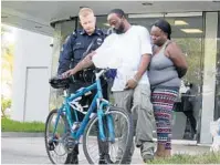  ??  ?? Pembroke Pines Sgt. Christophe­r Sengelmann, Octavius Veargis and Andrea Fussell, son and neice of David Lee Veargis, look at the bike David was riding on when he was killed by a hit-and-run driver.