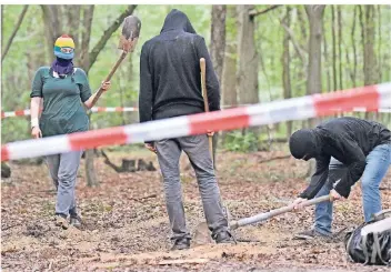  ?? FOTO: AP ?? Vermummte Klimaaktiv­isten heben im Hambacher Forst ein Loch im Boden aus. Die Besetzer rüsten sich für die geplante Rodung des Waldes im Oktober.